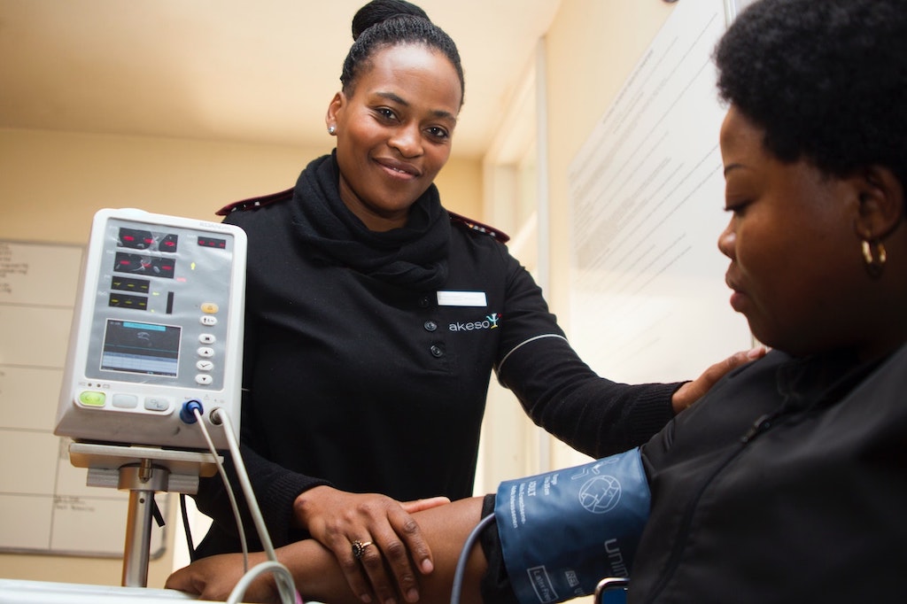 A smiling nurse attends to a patient