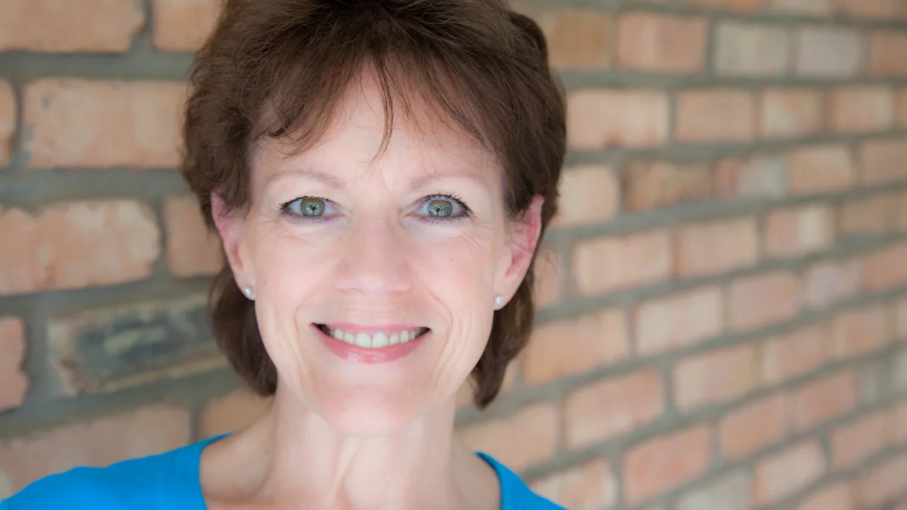 Susan Bennett smiles, backed by a brick wall
